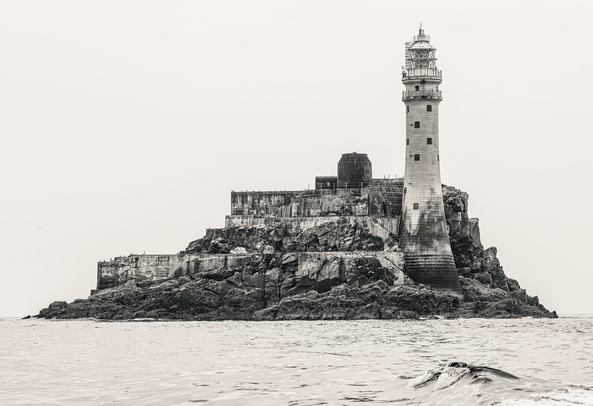 Lighthouse on an island with a fortification in the background