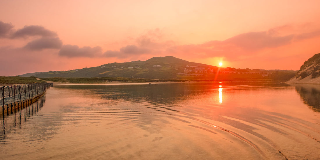 Sunset over a calm lake with mountains in the background