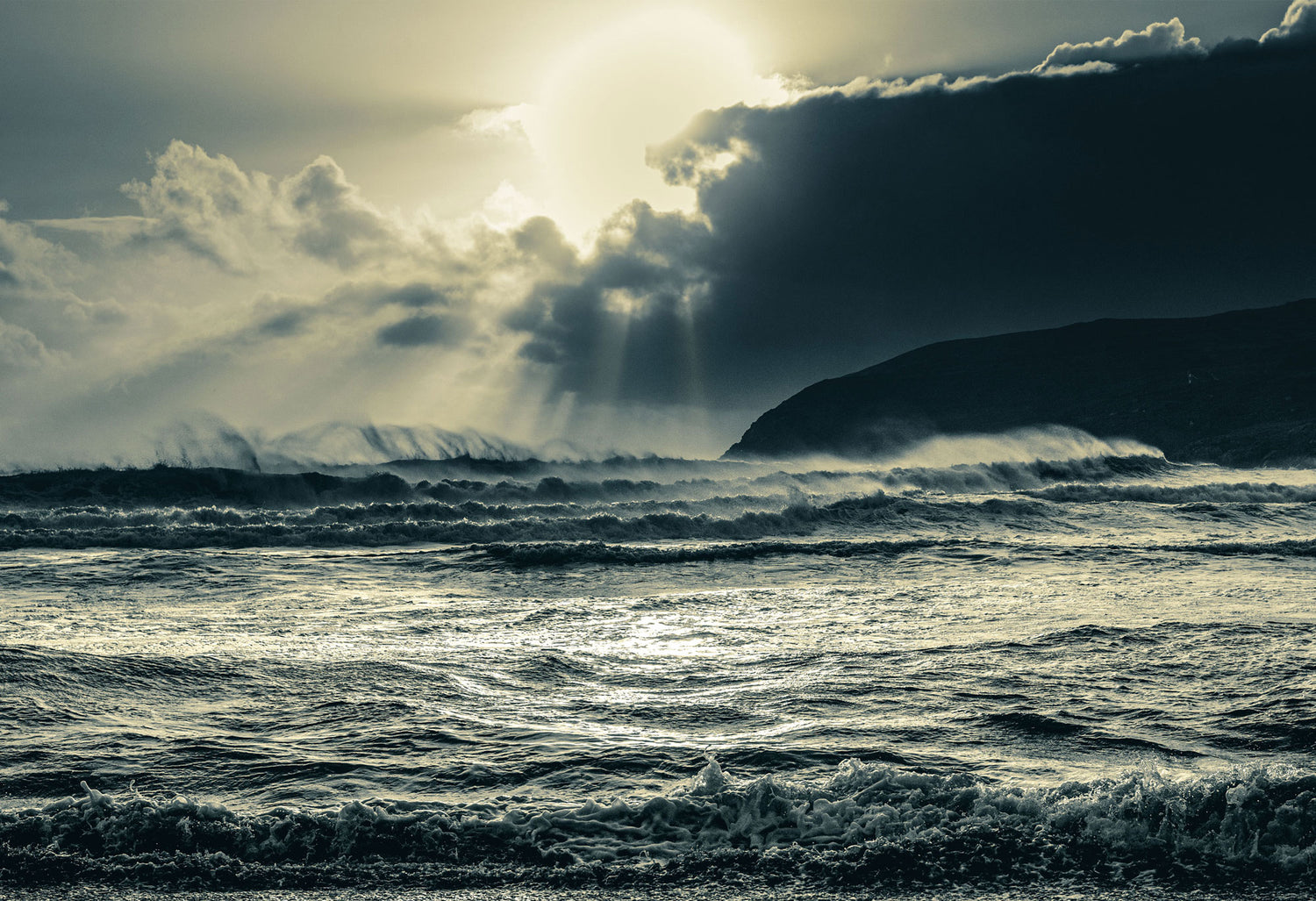 Stormy ocean with waves crashing against a cliff under a dramatic sky.